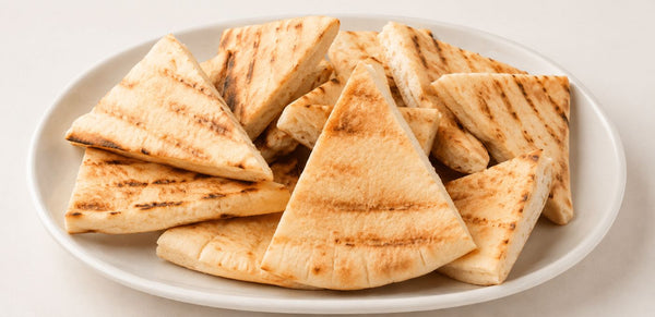 Grilled pita bread triangles arranged on a white oval plate against a light off-white background.