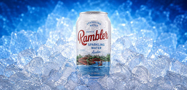 A can of Rambler Sparkling Water in Austin, Texas, standing upright in a bed of ice cubes against a blue, icy background.